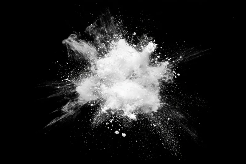 White powder exploding midair in burst pattern against black background