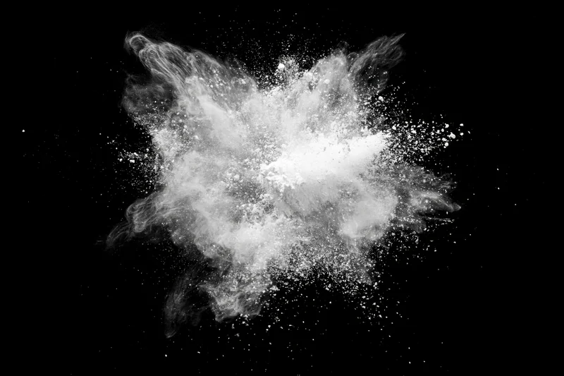 White powder exploding midair in burst pattern against black background