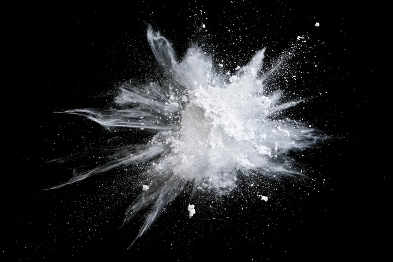 White powder exploding midair in burst pattern against black background