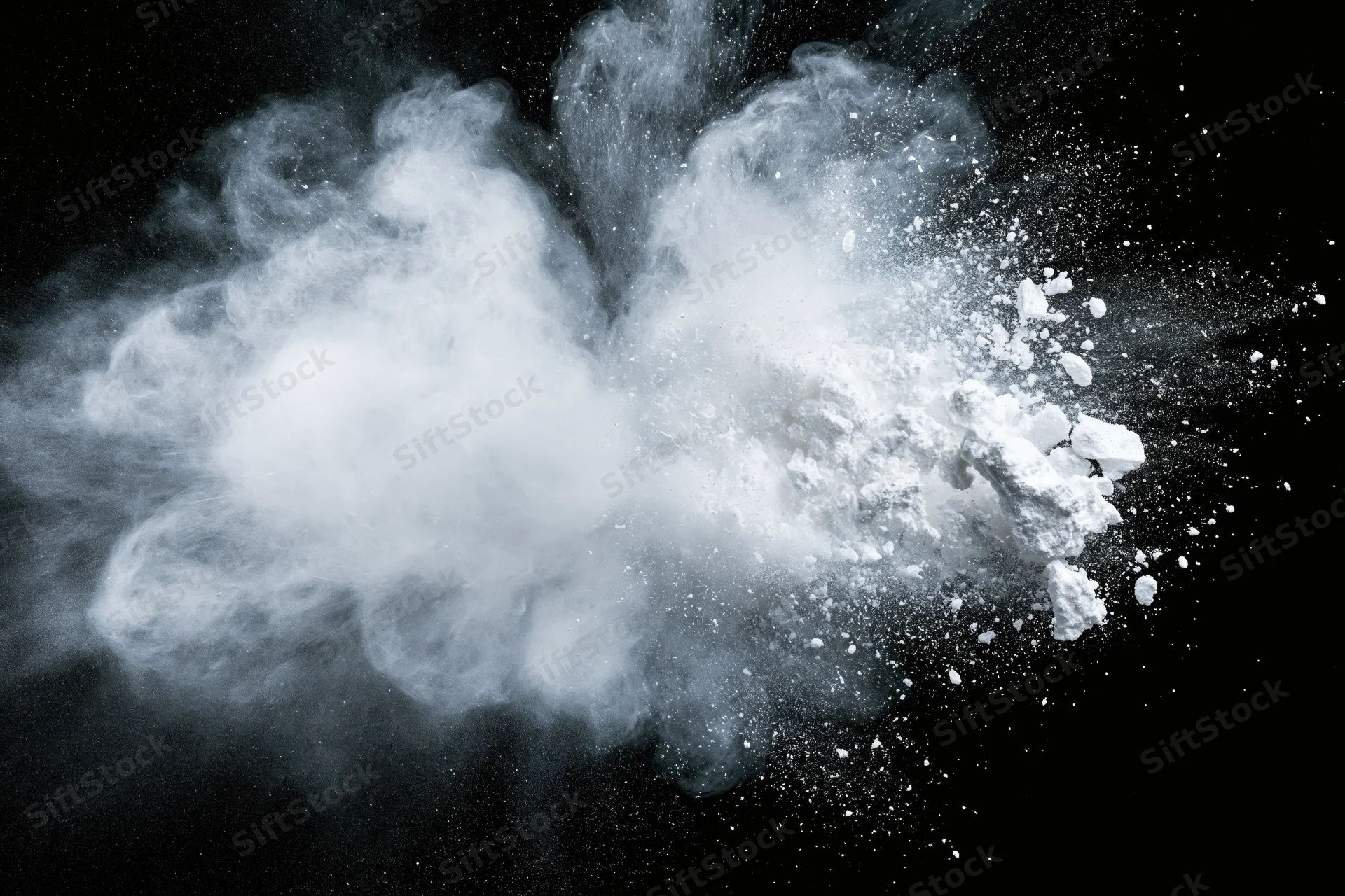 White powder exploding midair in a wide horizontal burst against black background