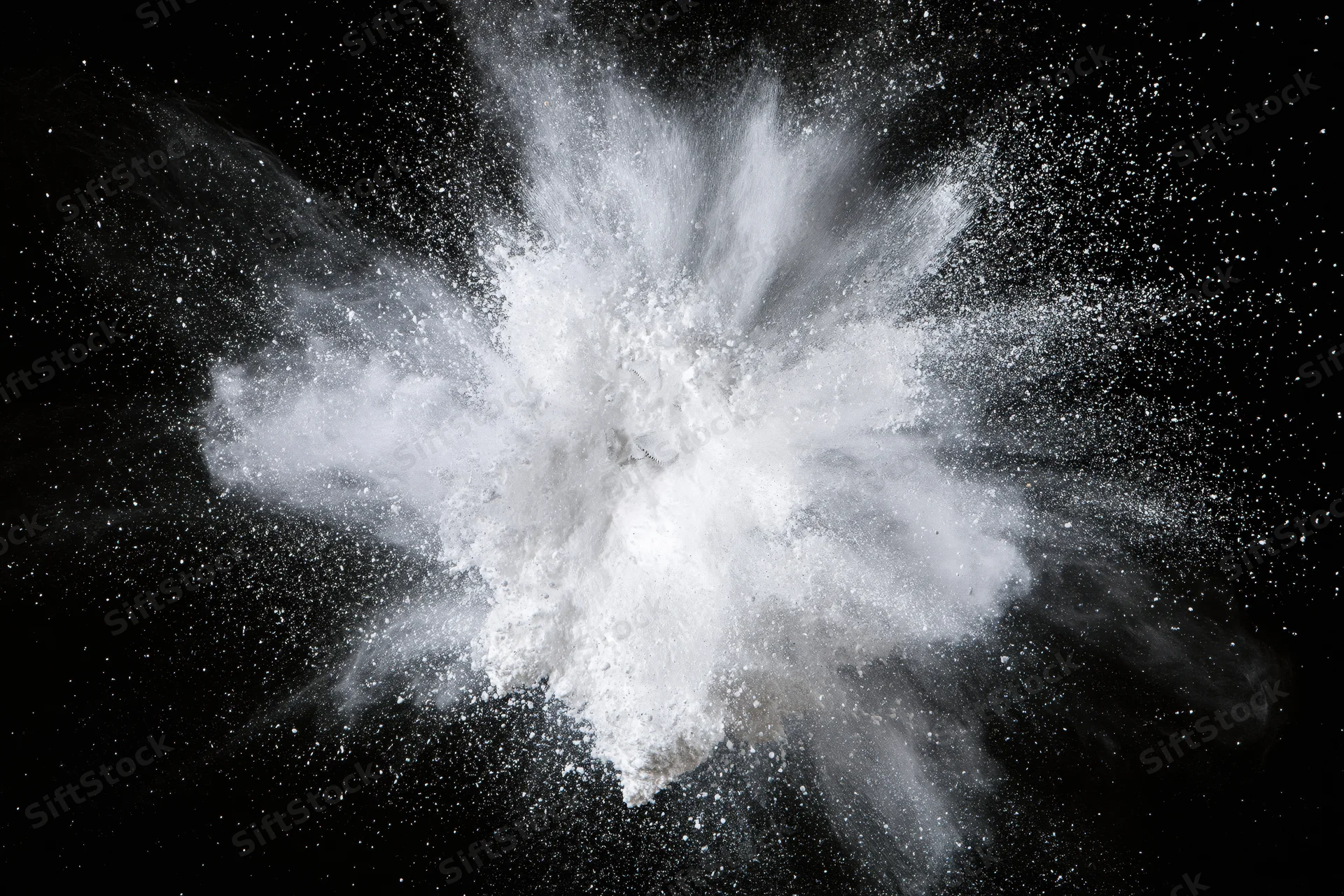 White powder exploding midair frozen in motion against black background