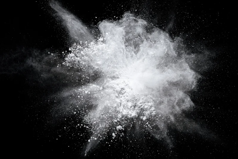 White powder exploding midair frozen in motion against black background