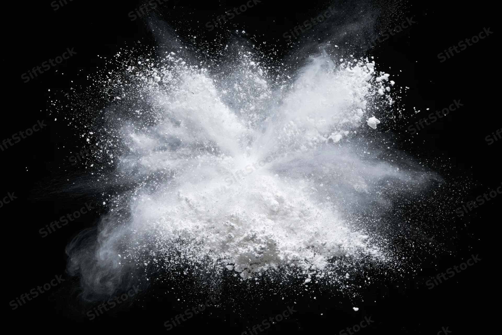 White powder exploding midair frozen in motion against black background