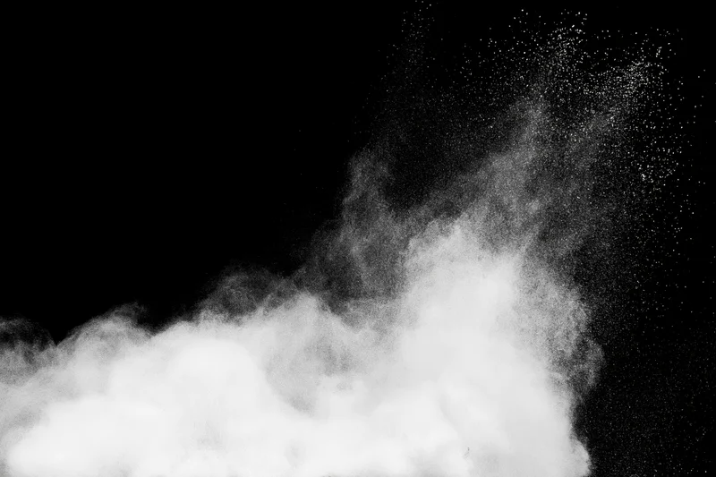 White powder bursting upward in mid-air against black background