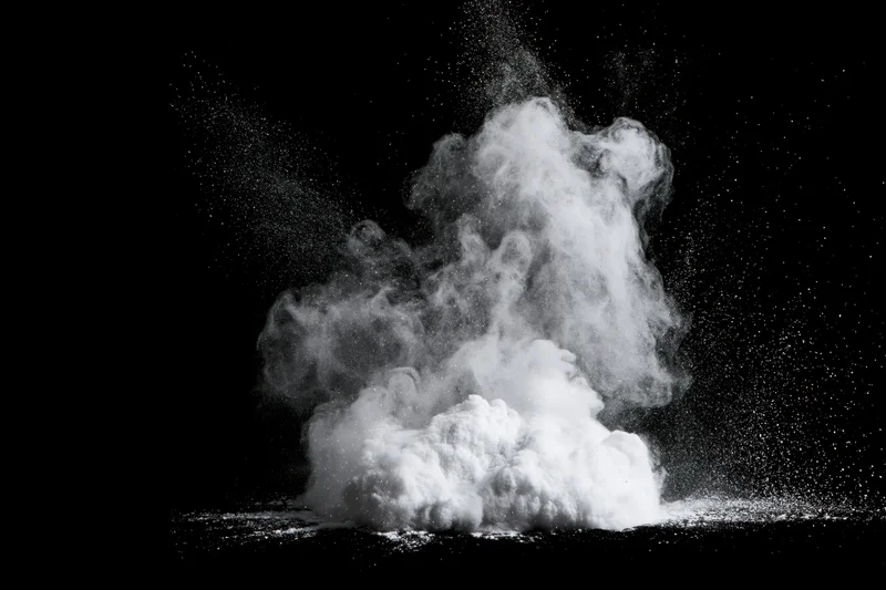 White powder exploding upward in mid-burst frozen in motion against black background