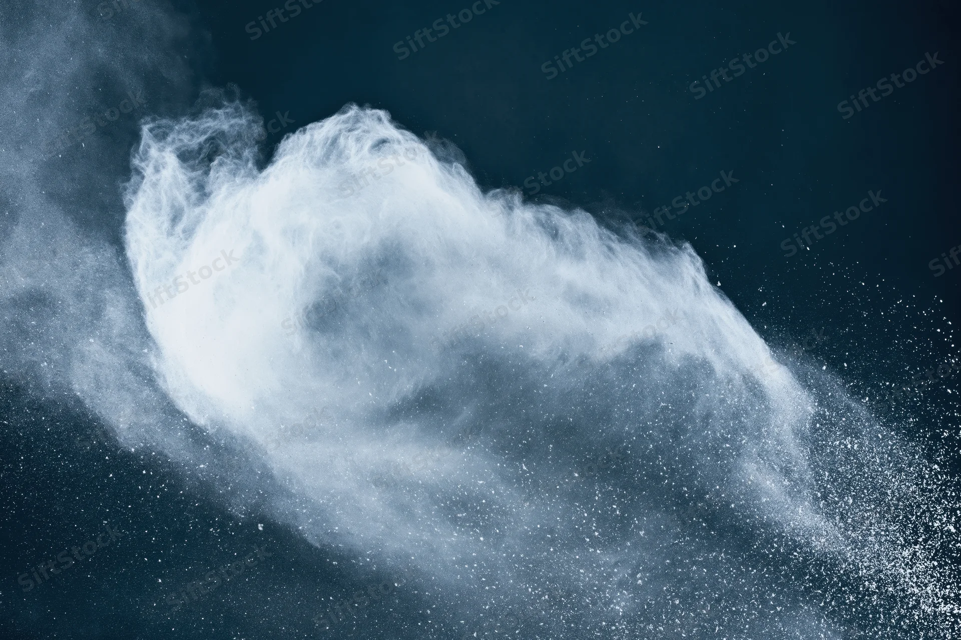 White powder exploding in mid-air forming a sweeping arc against a dark background