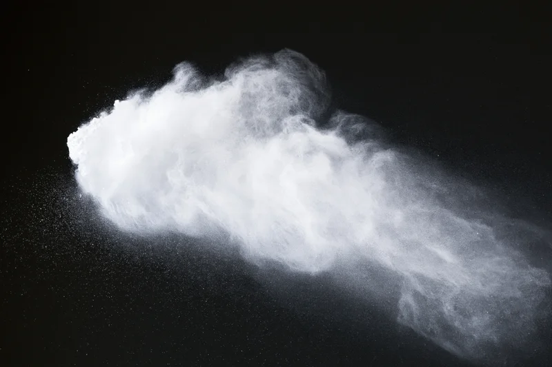 White powder exploding in mid-air against black background