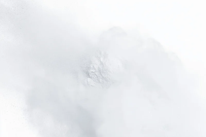 White powder bursting into airborne cloud against pure white background