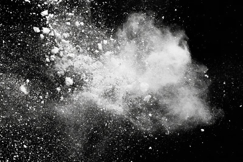 White powder exploding midair against a pure black background