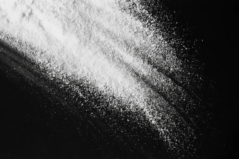 White powder scattered diagonally across a black surface