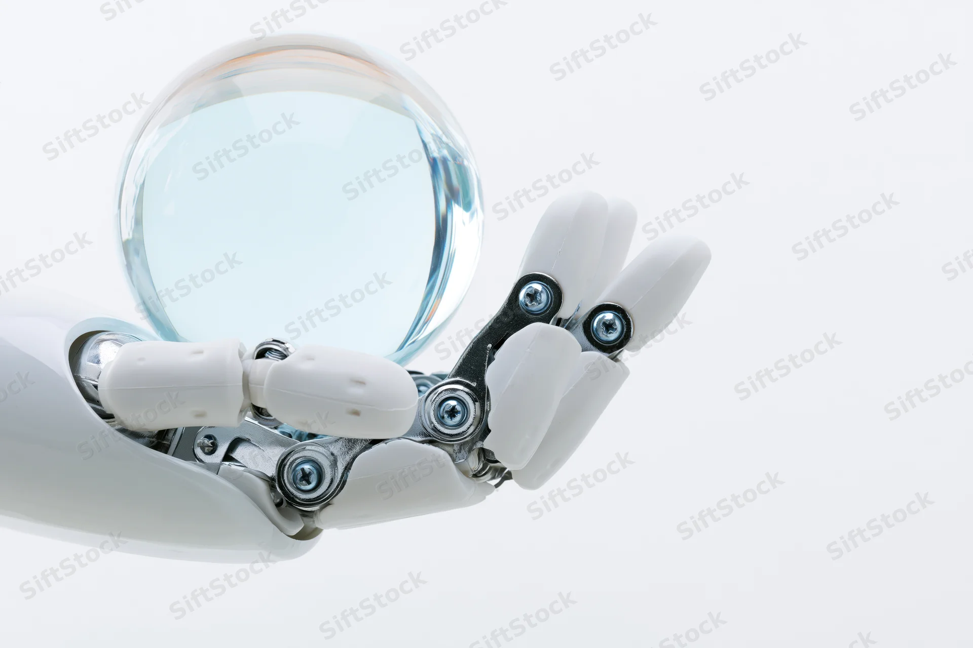 Robotic hand holding a transparent glass sphere against white background