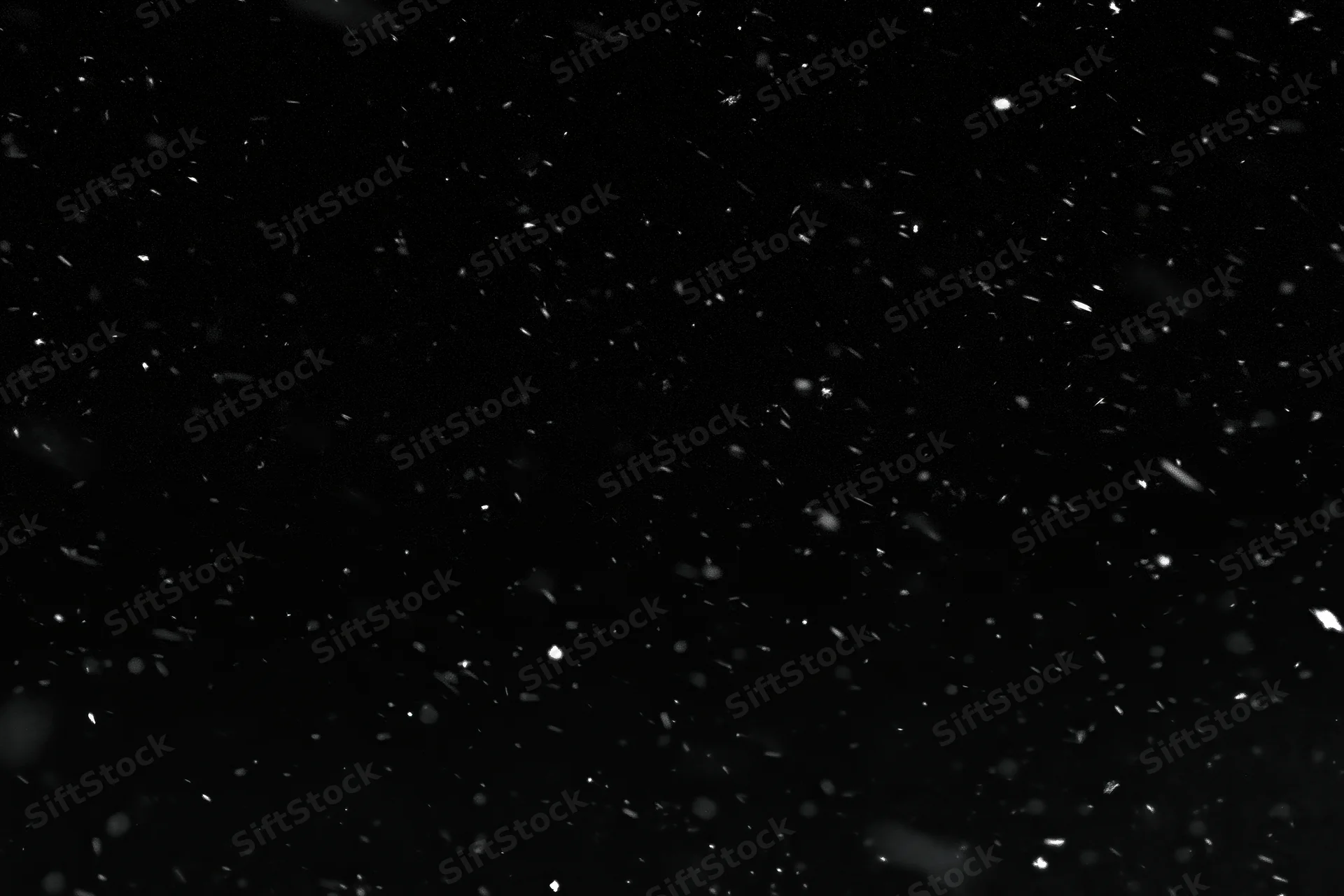 Snowflakes falling against a black background