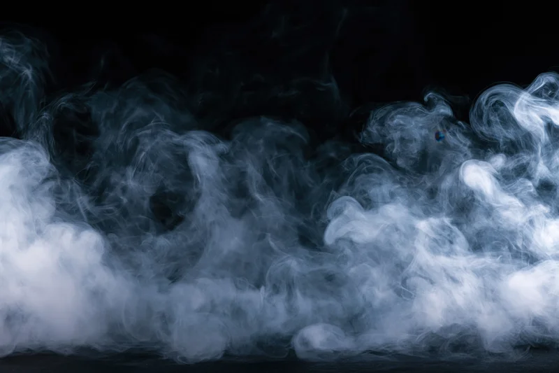 Wisps of white and grey smoke drifting and curling across a dark background