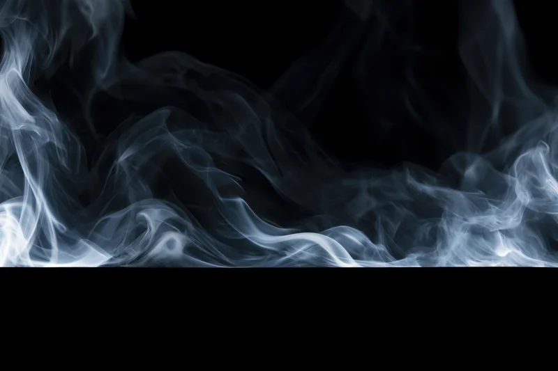 Wisps of white and grey smoke drifting and curling across a black background