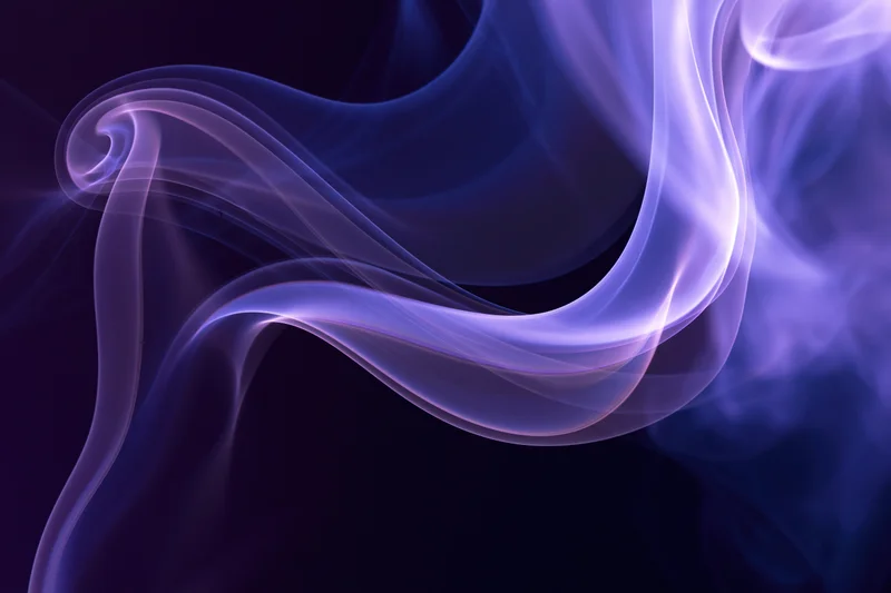 Wispy purple and blue smoke tendrils curling and flowing in an abstract pattern against a dark background