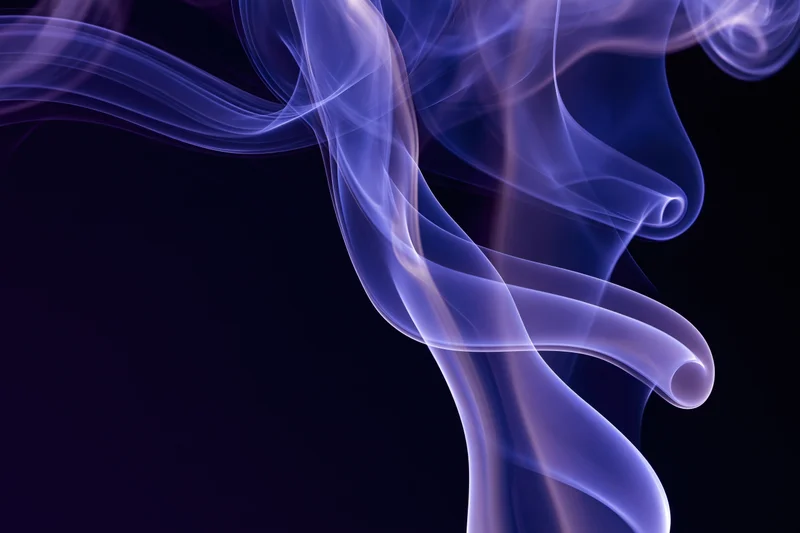 Wispy purple smoke tendrils curling and flowing against a dark background