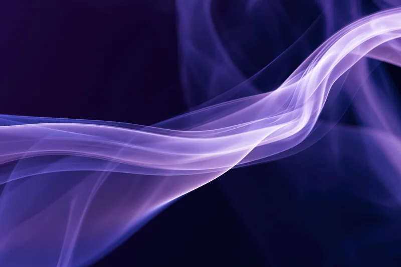 Wispy purple smoke tendrils flowing in abstract motion against dark background