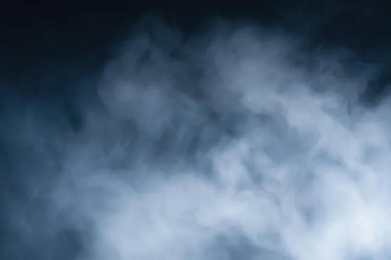 Wispy white smoke drifting through dark air