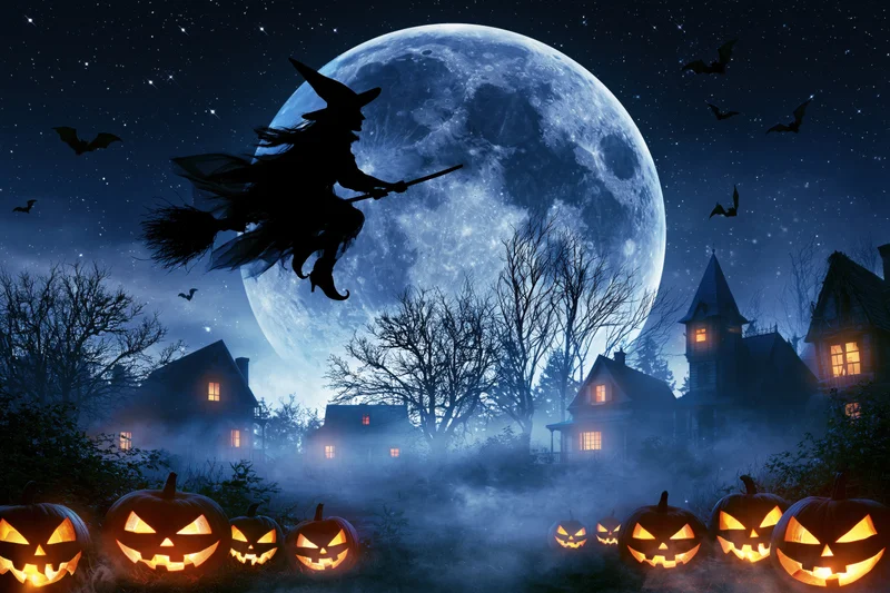 Witch silhouette flying on broomstick across full moon over foggy village with glowing pumpkins and bats