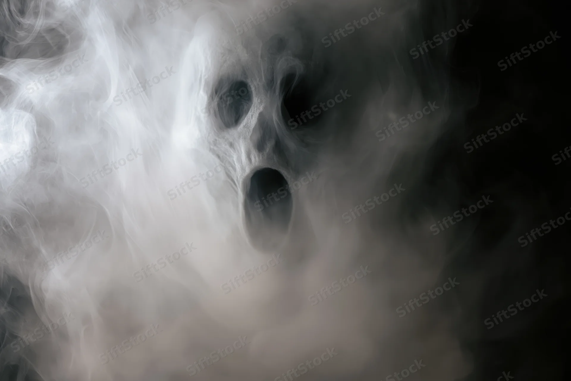 Ghostly face emerging from swirling white smoke in dark atmosphere