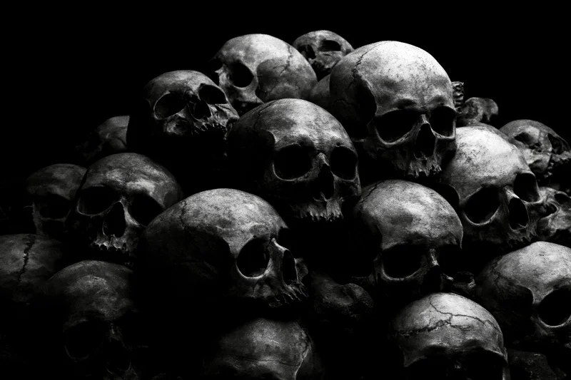 A pile of aged human skulls stacked together in dark lighting