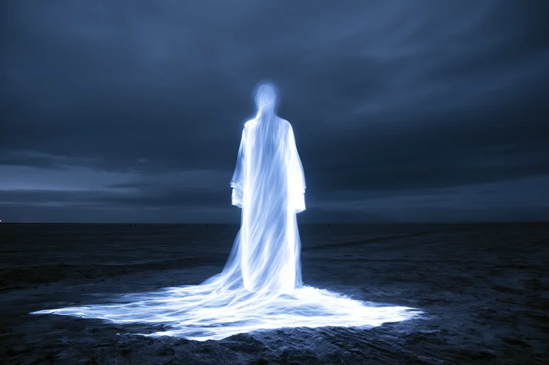 Glowing spirit figure standing on a dark beach at night