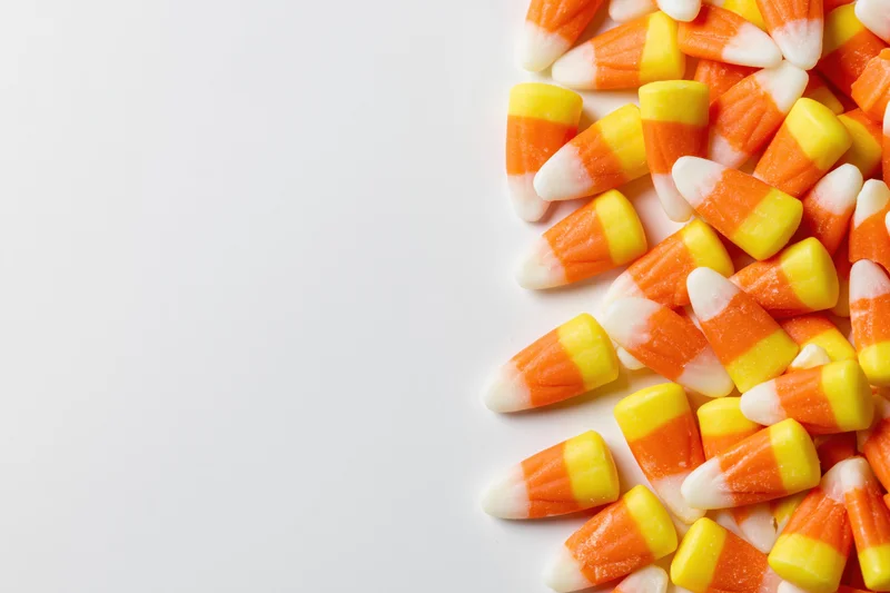 Candy corn pieces scattered along the right side on a white background