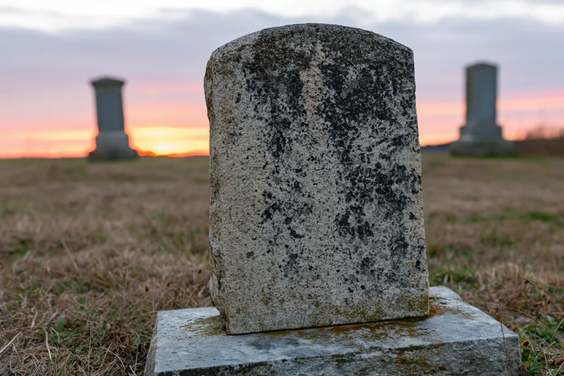 Weathered gravestone with lichen and moss in a cemetery at sunset