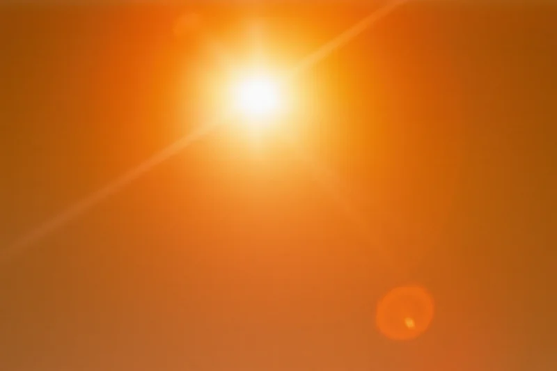 Blazing sun in a hazy orange sky with lens flare and no visible horizon