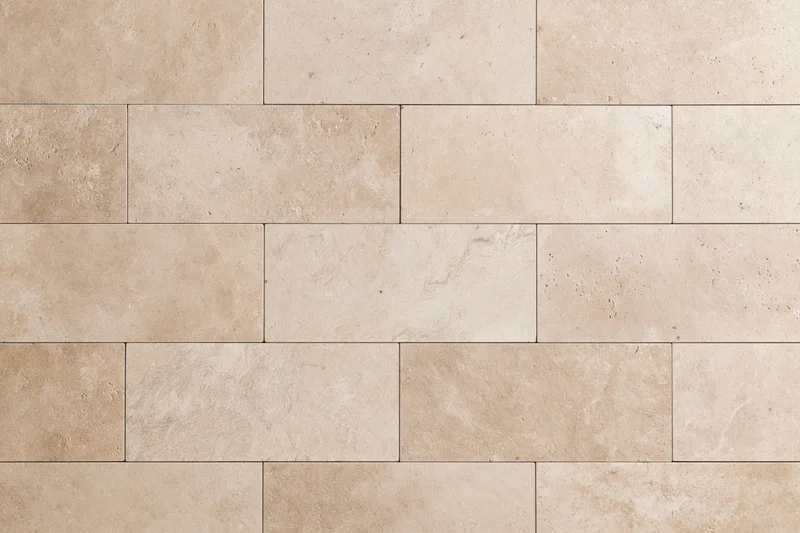 Close-up of travertine stone tiles arranged in a rectangular pattern on a wall