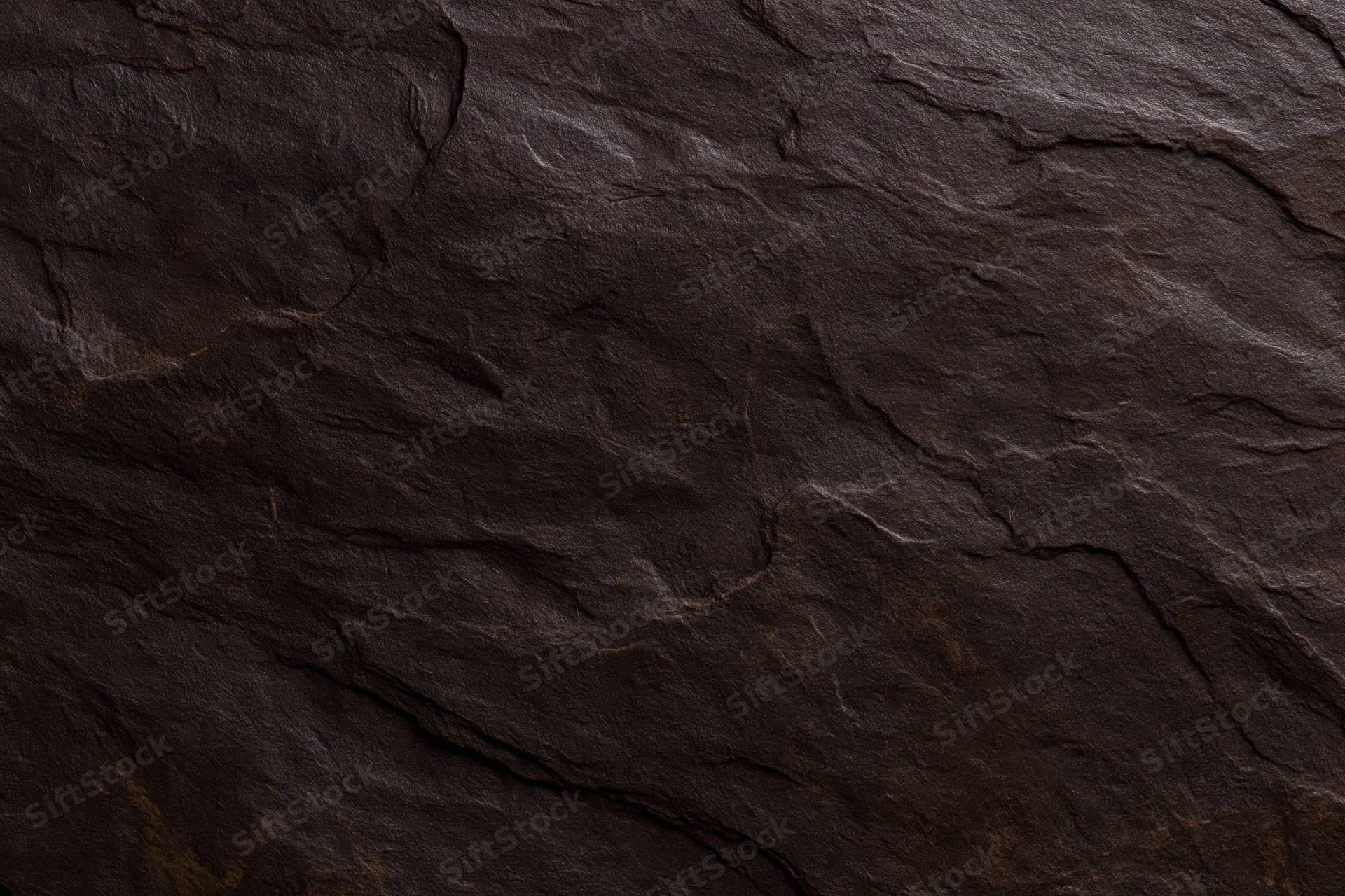 Close-up of dark brown slate stone surface with natural cracks and layered texture