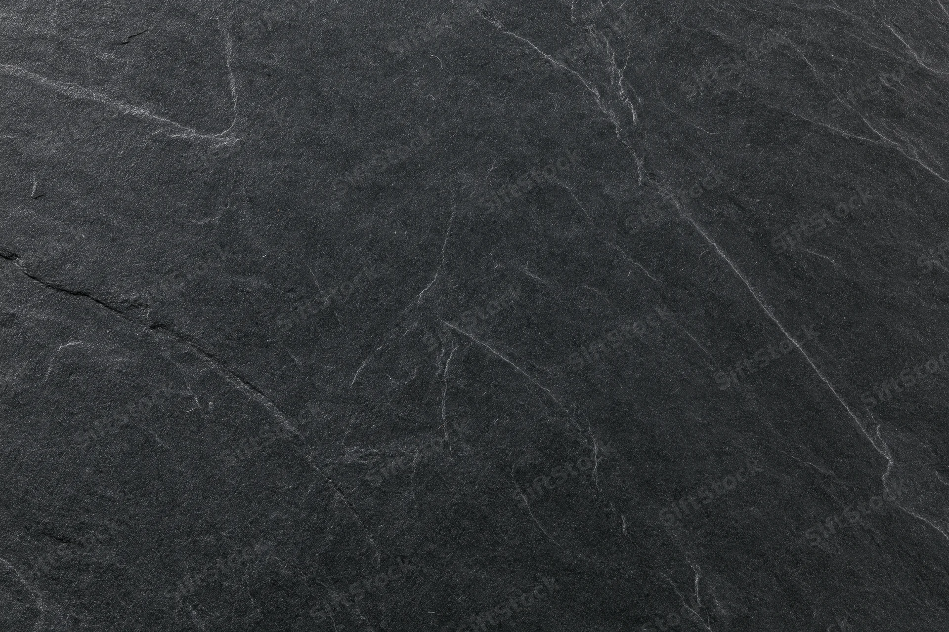 Close-up of dark slate stone surface with natural veins and cracks