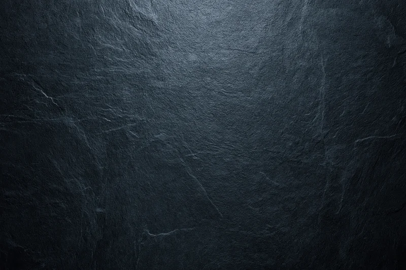Dark slate stone surface with natural texture and subtle lighting variations