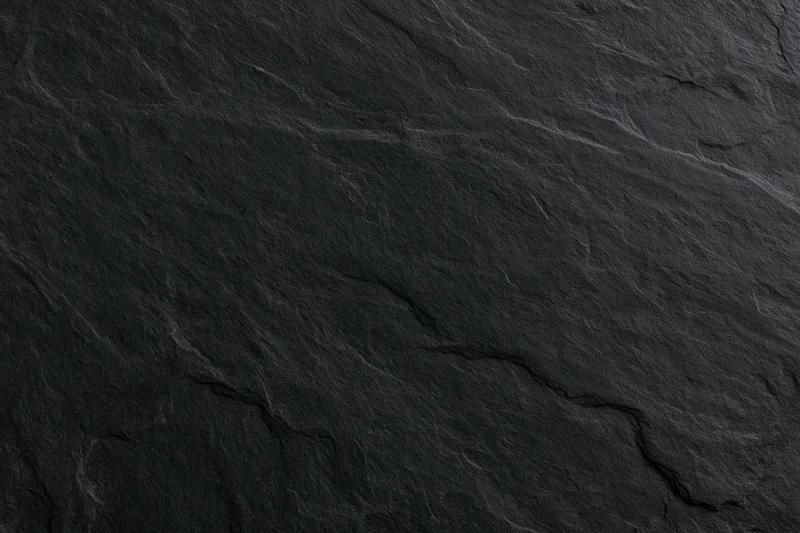 Close-up of dark slate stone surface with natural cracks and veins