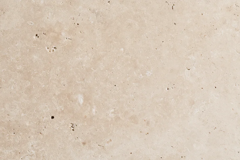 Close-up of travertine stone surface with natural veining and porous texture filling the frame