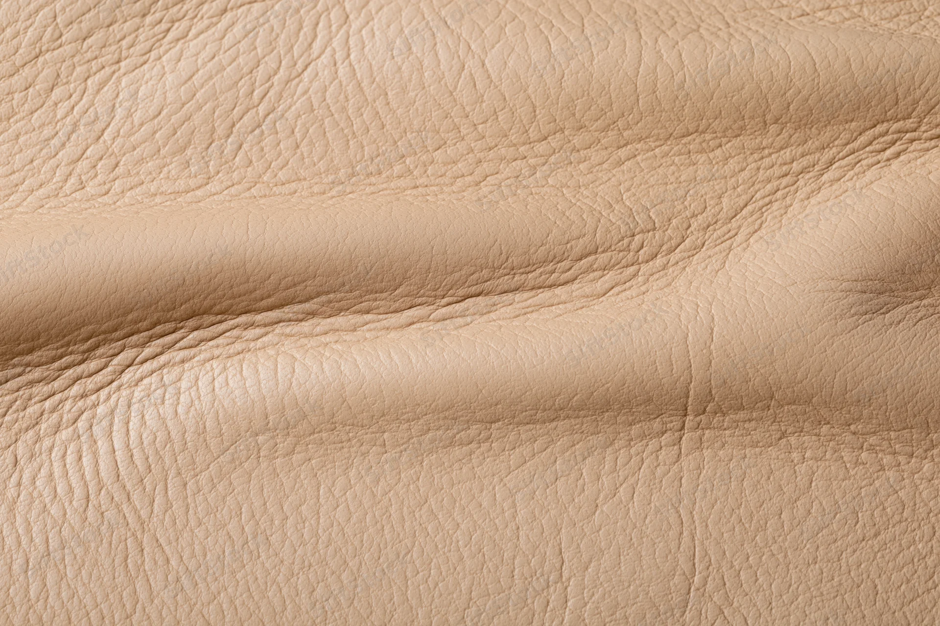 Close-up of aged beige leather surface with natural grain and folds
