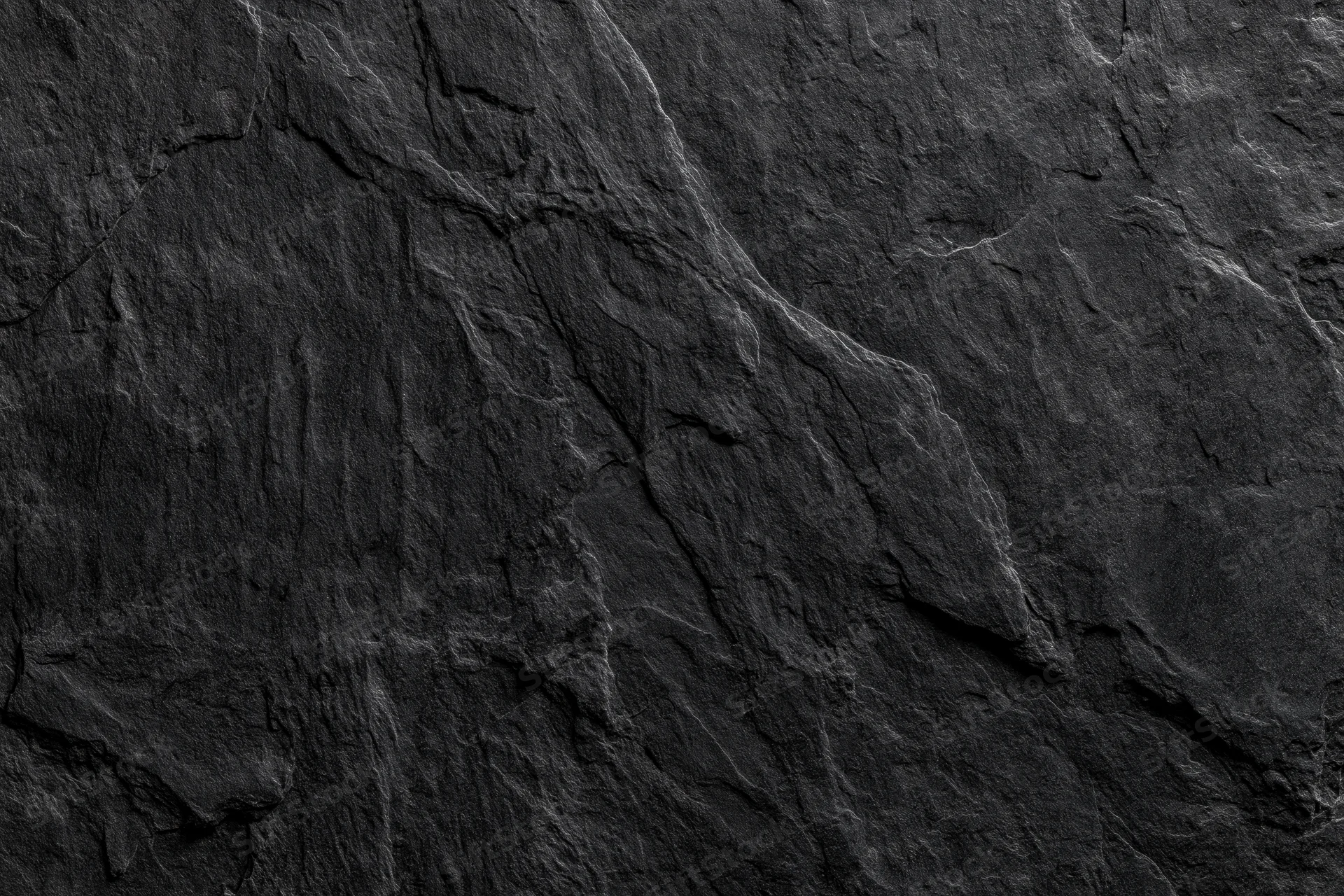 Close-up of dark slate rock surface with natural cracks and layers