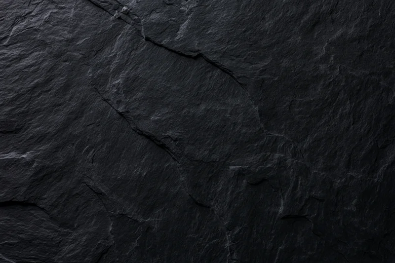 Close-up of dark slate rock surface with natural cracks and texture filling the frame