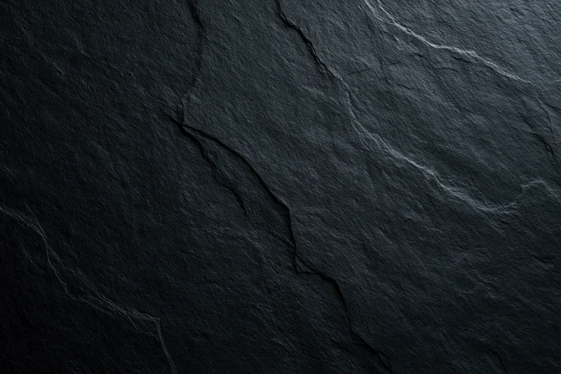 Close-up of dark slate rock surface with natural cracks and veins filling the frame