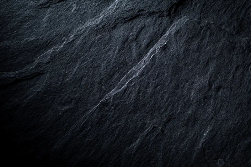 Close-up of dark slate rock surface with natural veins and cracks filling the frame