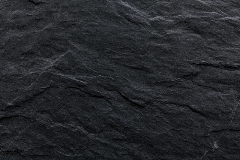 Close-up of dark slate stone surface with natural texture and cracks filling the frame