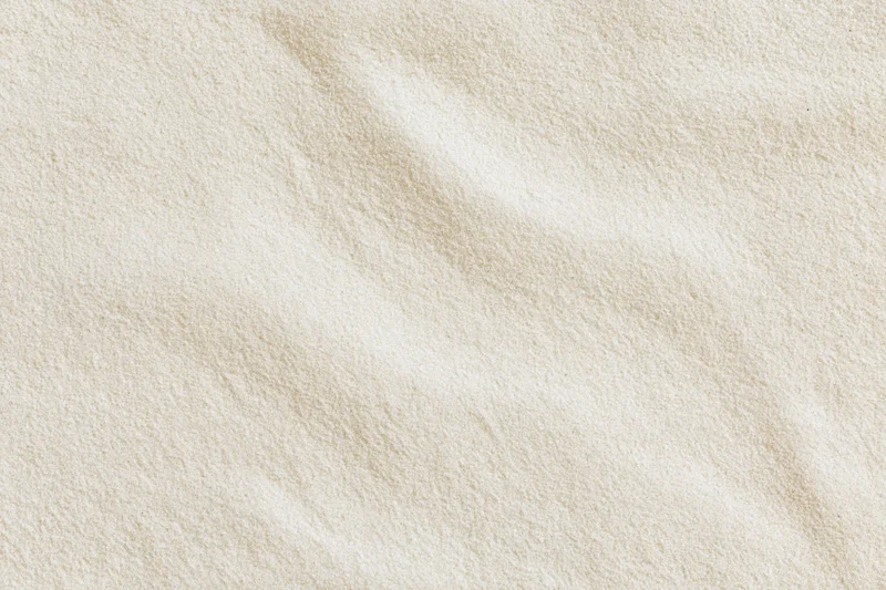 Close-up of fine beach sand surface with natural texture and subtle ripples