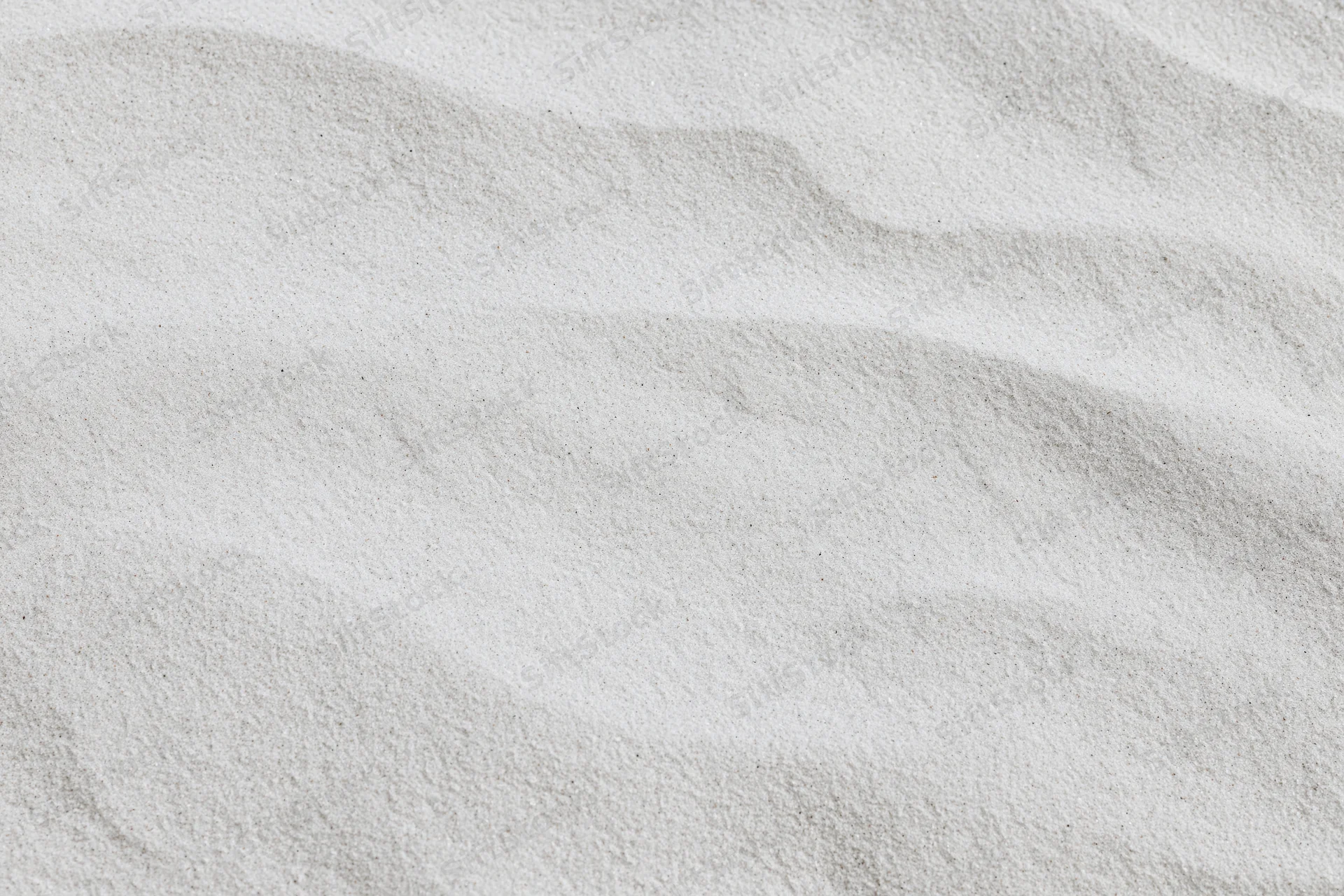 Close-up of fine white beach sand with undulating texture filling the frame