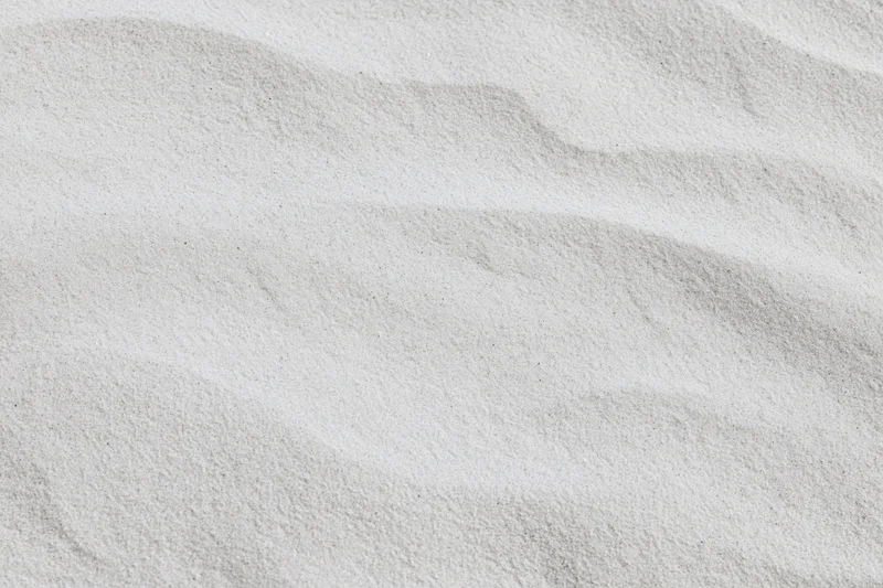 Close-up of fine white beach sand with undulating texture filling the frame