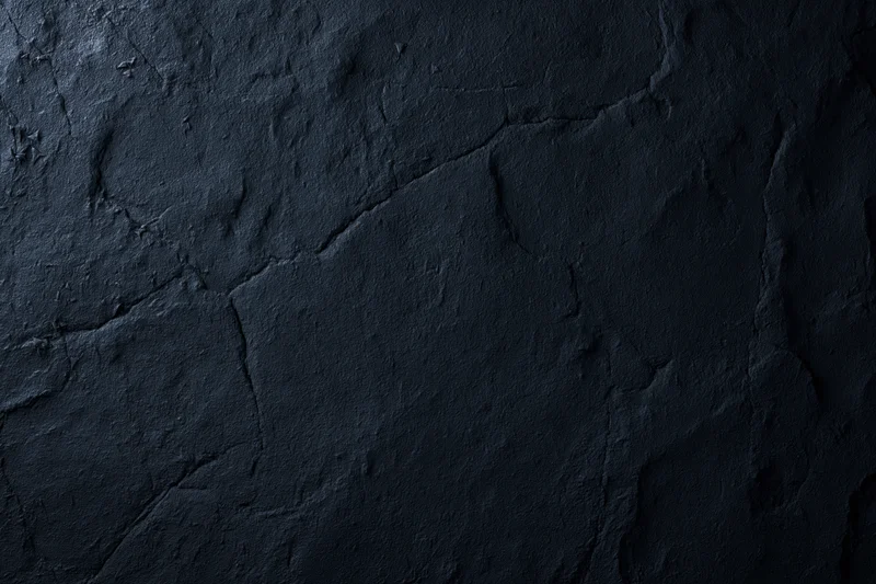 Close-up of dark rough stone or plaster surface with cracks and texture