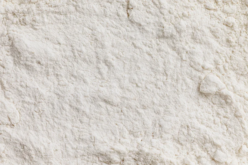Close-up of white wheat flour spread evenly across a flat surface