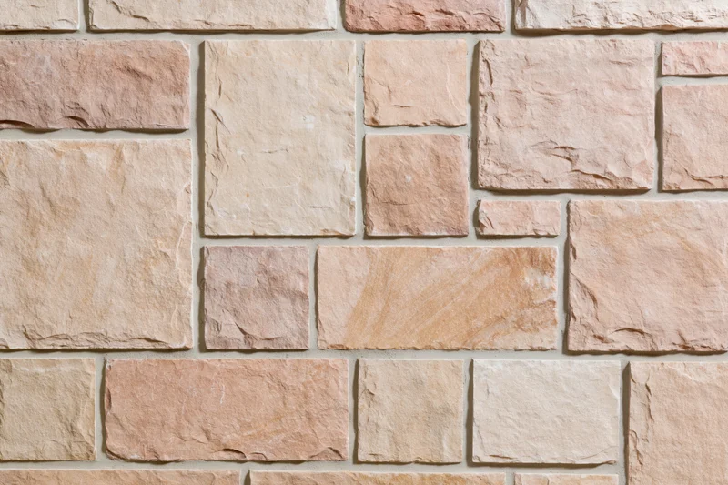 Close-up of a cut stone wall surface with rectangular tiles in beige and pink tones