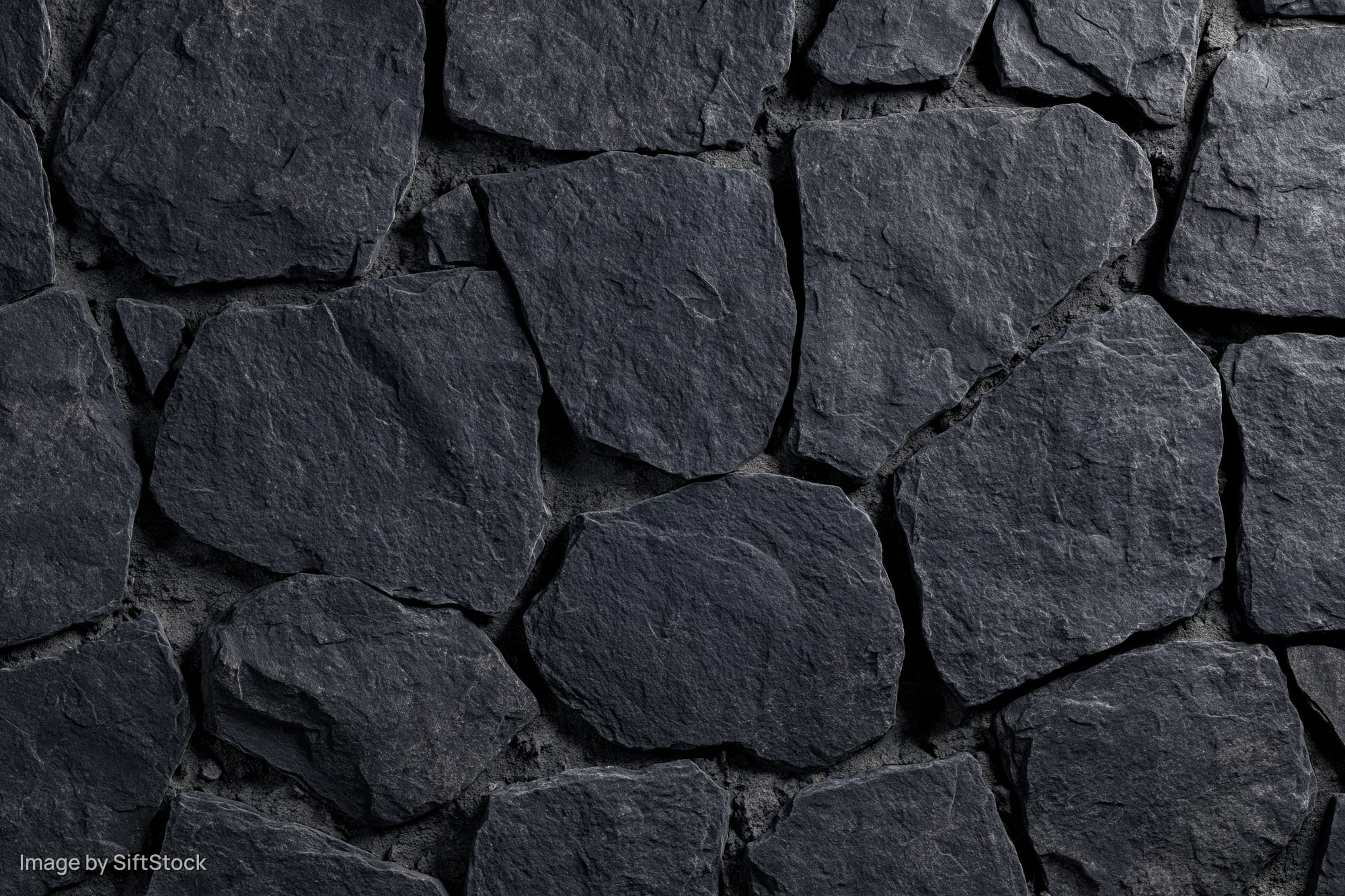 Close-up of dark irregular slate stone wall surface