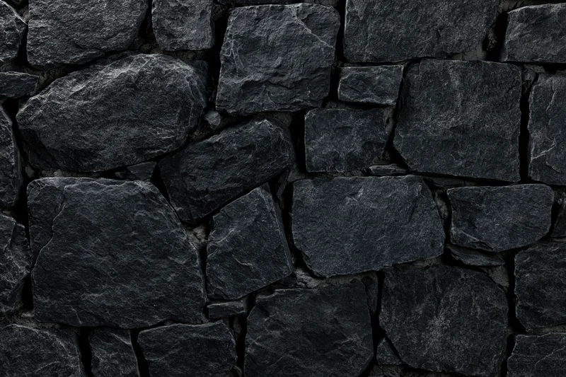 Close-up of dark slate stone wall with rough irregular texture