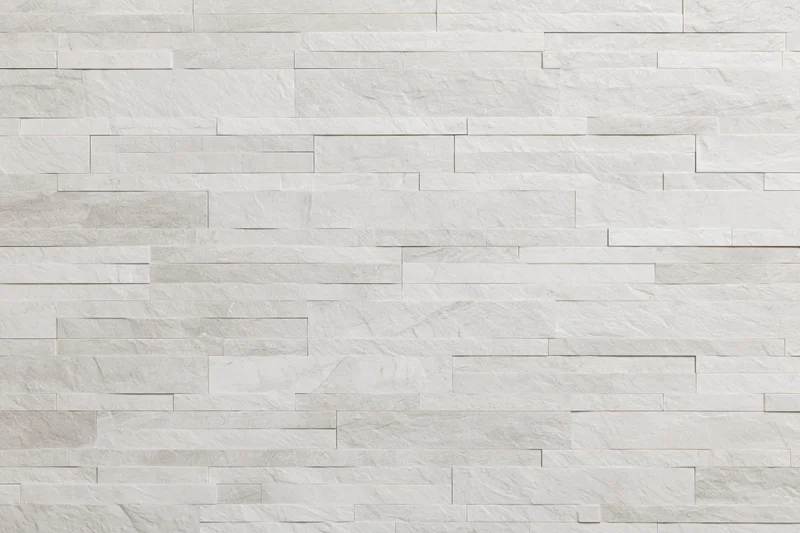 Close-up of a modern stacked stone tile wall with horizontal rectangular slabs in white and light gray tones